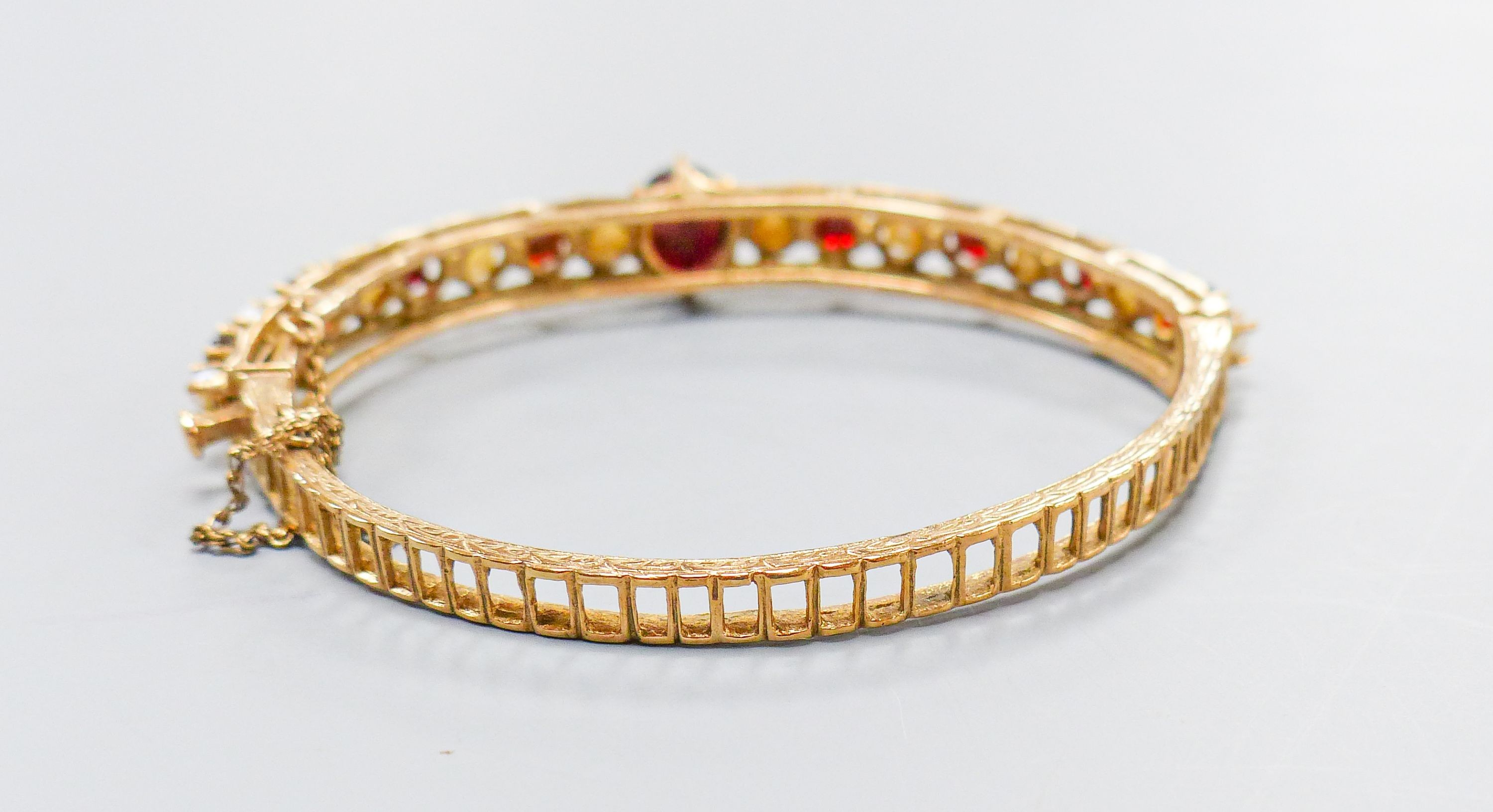 A 9ct gold, garnet and cultured pearl set hinged bracelet, gross weight 16.1 grams.